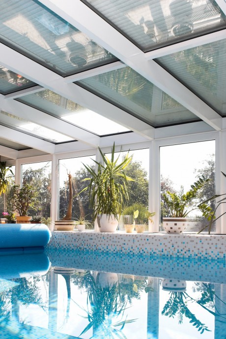 Předokenní rolety střešního typu: Předokenní rolety na střešním skle chránící bazén před sluncem
